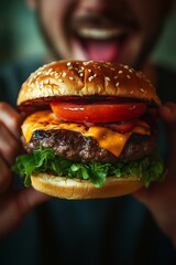 An excited young man bites into a juicy hamburger, melted cheese, fresh lettuce and tomato. The sharp details and high resolution create a fun and lively mood.
