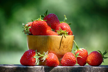 Fresh strawberries overflowing a wooden bowl on a railing
