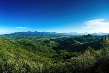 Obraz premium Panoramic vista of rolling hills and valleys under a vibrant blue sky
