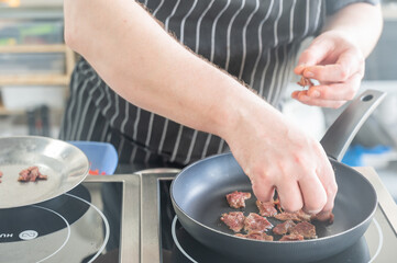 The chef fries veal in a frying pan. 