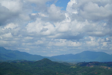A scenic view of rolling hills and mountains under a cloudy sky.