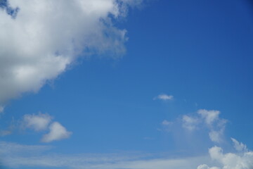 A bright blue sky with fluffy white clouds scattered throughout the frame, creating a serene and...
