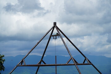 Metal pyramid structure against a backdrop of cloudy sky and distant mountains.