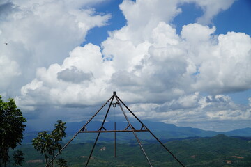 Metal structure atop a hill overlooking a lush green landscape with a cloudy sky.