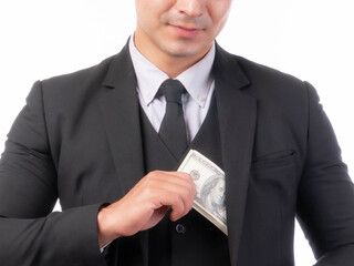 A well-dressed businessman in a black suit discreetly placing US dollar bills into his jacket...