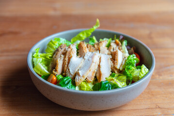 Grilled chicken breast salad, green vegetable healthy menu. Diet food on wood table background,