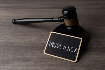 A judge's gavel and a chalkboard with text INSOLVENCY. Legal proceedings, financial regulations,...
