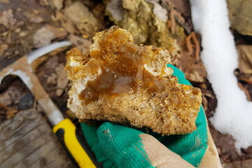 Chipped piece of brown chalcedony in hand, geological hike for rock and mineral samples