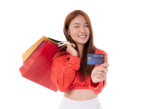 A cheerful young Asian woman with long brown hair, holding colorful shopping bags and a credit card, smiling , isolated on a transparent background, ready for a shopping spree