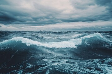 Fototapeta premium Rolling ocean waves crash under a dramatic cloudy sky near the horizon during an overcast day, Rolling ocean waves under cloudy sky