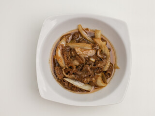 Stir fries meat and onion with sweet sauce on white plate