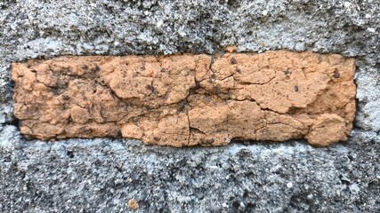 Crumbling concrete wall with exposed red brick details. Rugged surface texture suitable for...
