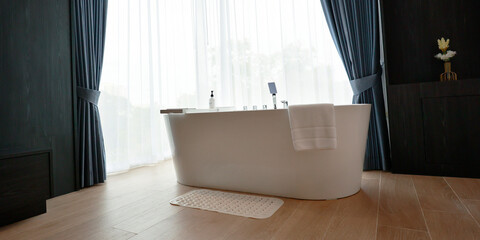 a white bathtub near a window with curtain