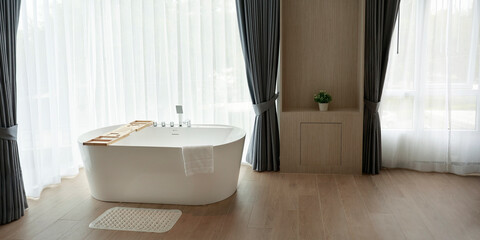 a white bathtub near a window with curtain
