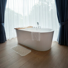 a white bathtub near a window with curtain