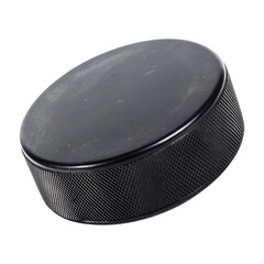 A well-worn black hockey puck against a stark black background showcases the texture and details of this iconic sports equipment.