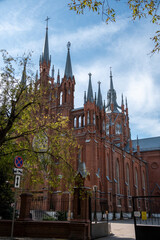 Gothic Revival church featuring multiple spires and intricate brick facade. The structure is...