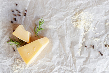 parmesan cheese rosemary and black peppercorns on white crumble baking paper background.