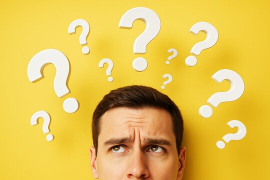 Confused young man looking up with white question marks above head on bright yellow background, symbolizing problem solving or decision-making concept.