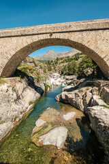 The Ponte Altu bridge at Albertacce on the Mediterranean island of Corsica passing over the crystal clear Golo river with Monte Albanu in the distance