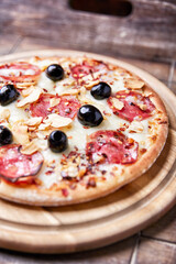 Pizza with salami and mozzarella cheese. Wooden background. Soft focus. Close up.	