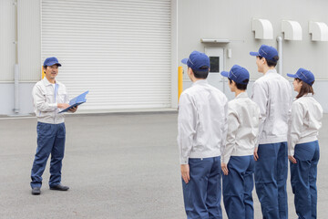 工場の前で朝礼をする作業員グループ