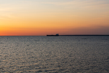 Maritime freight transport on the Baltic Sea. Silhouette of a large oil tanker on the horizon during a quiet and colorful sunset.