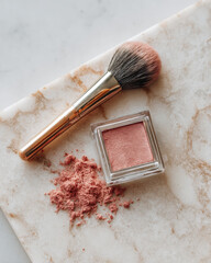 Beautiful flat lay featuring soft pink blush powder, fluffy makeup brush, and marble surface. delicate colors and textures create inviting and elegant aesthetic for beauty enthusiasts