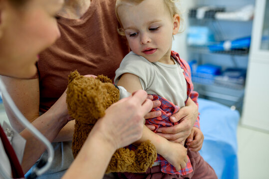 Doctor placing cotton and medical tape on the injection spot. - Powered by Adobe