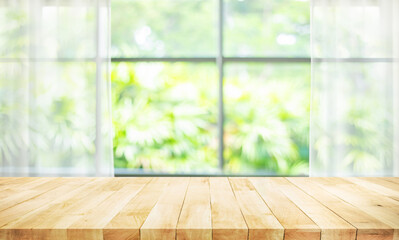 Selective focus.Wood table counter top on blur curtain window with green troptcal garden background.