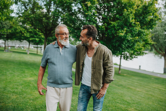Senior dad and middle-aged son enjoying peaceful walk in park.