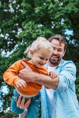 Father playing with toddler son outdoors in park
