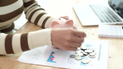 An Asian woman is putting money in a piggy bank while looking at a calculator, giving advice on financial planning.