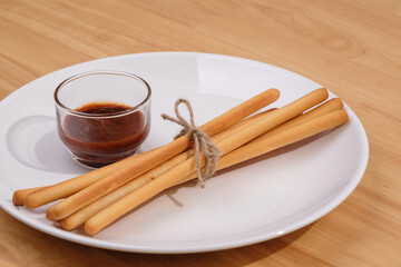 pack of breadsticks with ketchup dipping sauce in white dish on wood table