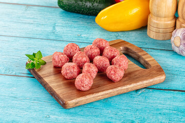 Raw beef meatballs over board