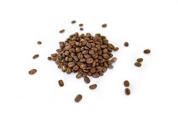 Closeup of a pile of organic whole roasted coffee beans isolated on a white background focused on the foreground