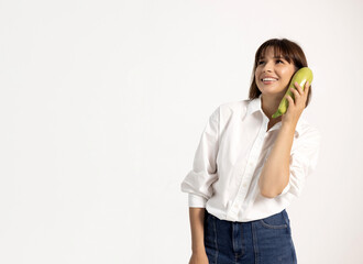 Woman holding a squash on her ear like a phone, smiling and pretending to talk. Promoting healthy...