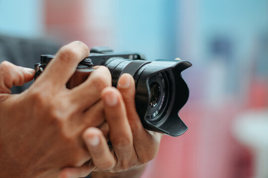 close up of hand holding mirrorless camera