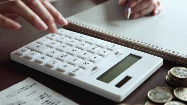計算機で会計をする女性の手　家計　計算機とレシートとお金　家計簿