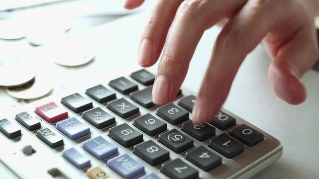 計算機で会計をする女性の手　家計　計算機とレシートとお金