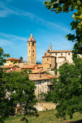 Bell tower rising above old houses under a blue sky in a small town of Monforte d'Alba, Italy.