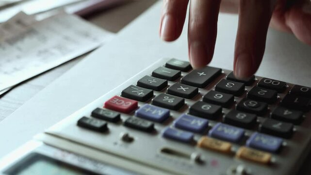 計算機で会計をする女性の手　家計　計算機とレシート　支出　コスト