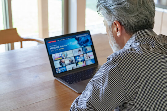 ノートパソコンで動画配信サービスを見るシニア男性