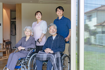 外を眺める車椅子に乗ったシニアカップルとケアスタッフ