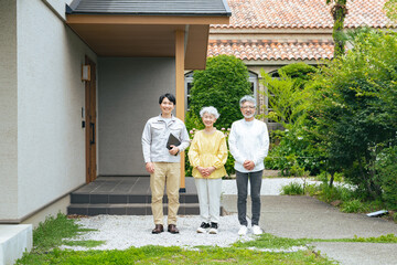 住宅の前で笑う男性作業員とシニアカップル