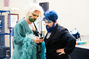 Bearded Drag Queens Browsing a Phone in a Vibrant Queer Celebration