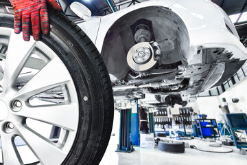 Wheel Alloy Tire Change in Auto Repair Garage, A mechanic hand holds a car wheel, removed from a...