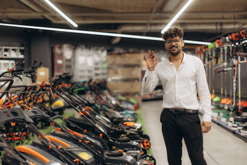 Smiling Employee Standing by Lawn Mowers Display in a Modern Store Setting