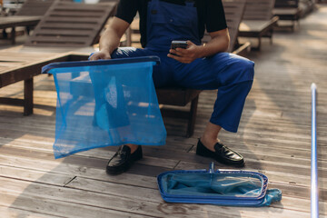 Pool cleaner checking smartphone and holding cleaning net