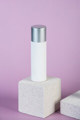 Plastic white tube for cream or lotion. Skin care or sunscreen cosmetic with stylish props on purple background.
